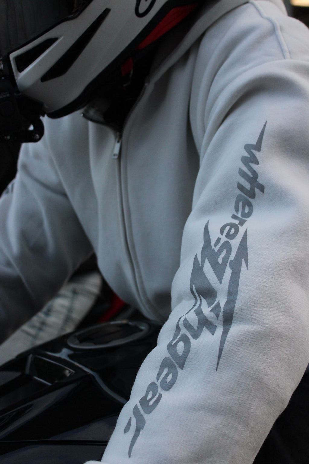 Close-up of the WHERES7THGEAR logo on a white hoodie sleeve